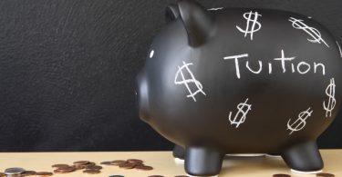 Piggy bank with dollar signs and "tuition" written on it.